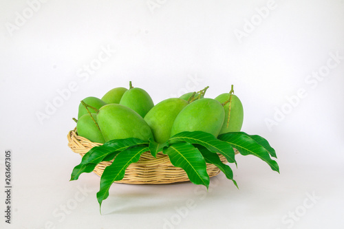 Green mango is in a wooden basket in a white background.