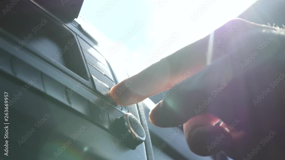 Man turns on the music in the car. Radio in the sun. Man's hand on the car key