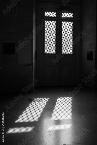 Indoor view of a door and its shadow on the floor   light from outside.