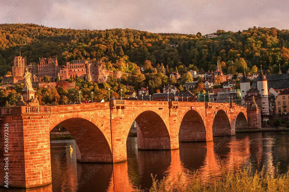 Panoramic view during red sunset at old bridge, downtown and castle in Heidelberg, Germany