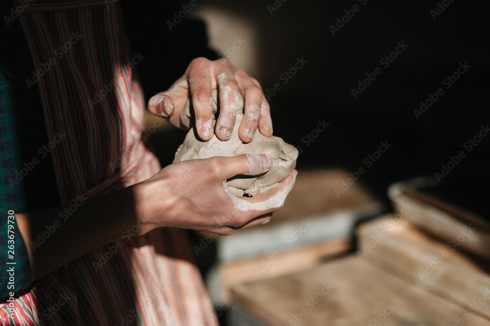 Close up of man works with clay. Male potter kneads and moistens the clay before work, toned