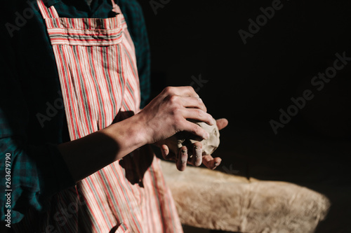 Close up of man works with clay. Male potter kneads and moistens the clay before work  toned