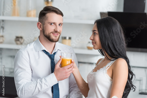 attractive brunette girl giving tasty orange juice to handsome man
