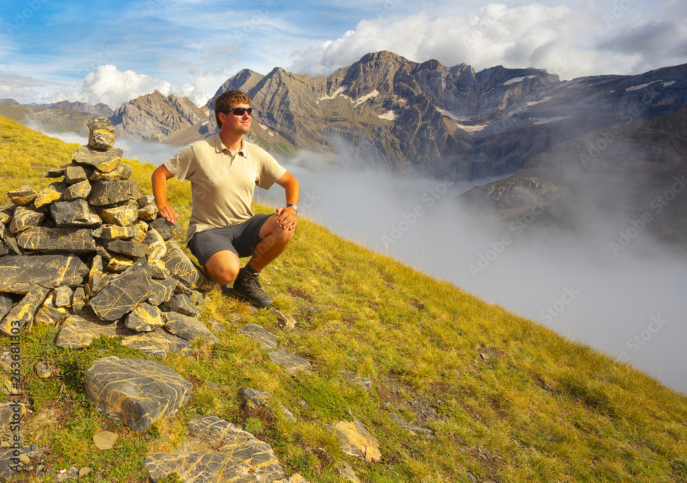 Naklejka premium Pyrenees; mountain; tourist; resting; sitting; man; relax; relaxing; watching; deep; valley; hiking; outdoor; landscape; Occidentales; rocks; rocky; fog; France; highland; level; stones; stony; upland