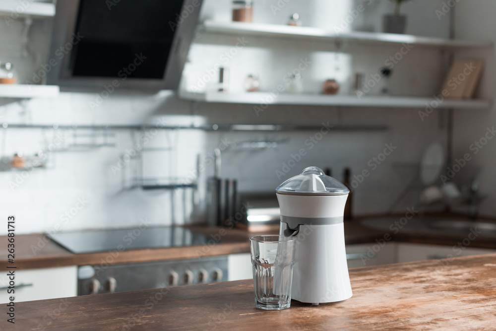 sunlight in kitchen with juicer and glass on wooden surface sunlight in kitchen with juicer and glass on wooden surface
