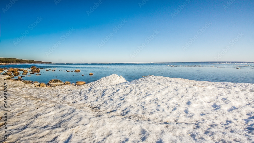 Snow pile, hill. Large snow drift isolated on a blue sky background,  outdoor view of ice blocks at frozen finland lake in winter