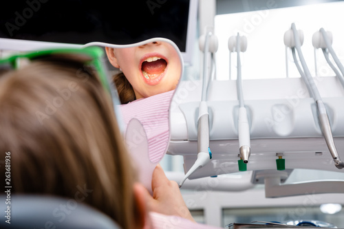 Preteen girl looking at her teeth in the mirror in pediatric dental clinic photo