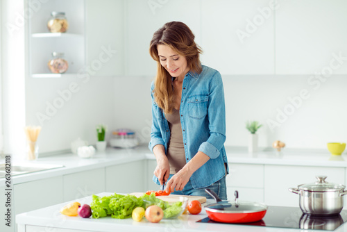 Portrait of her she nice lovely attractive cheerful brown-haired lady preparing new fresh recipe dish meal snack dinner lunch housekeeping in light white interior style kitchen