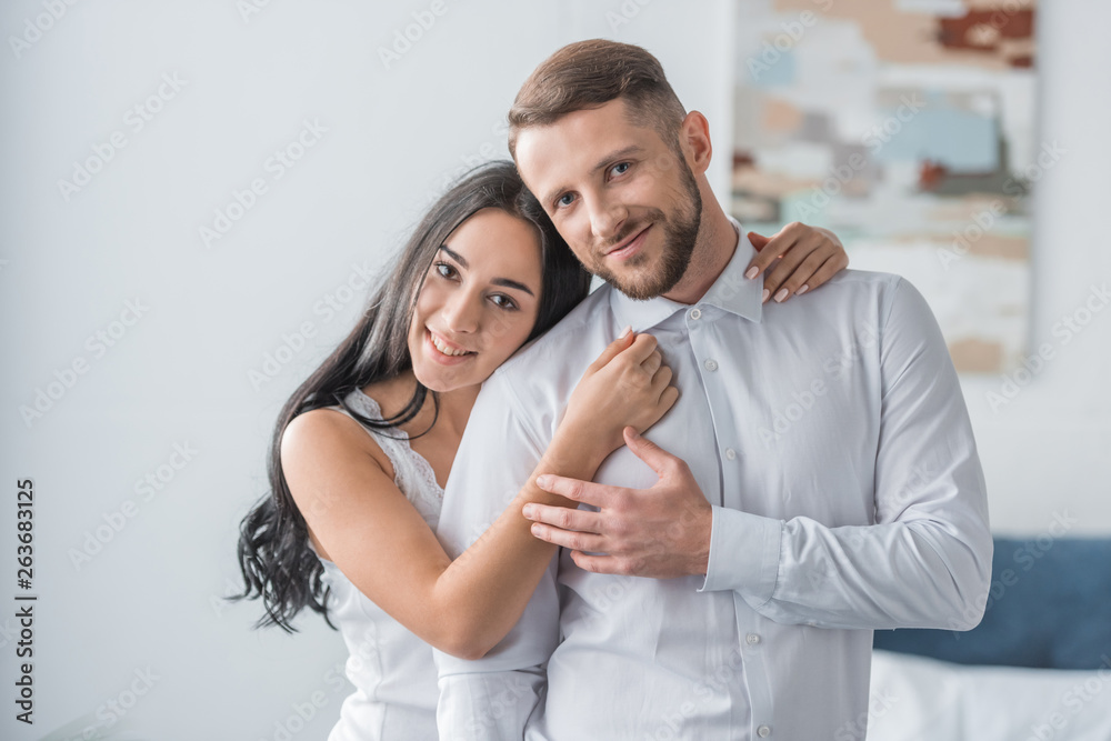 happy young woman hugging cheerful boyfriend in white shirt happy young woman hugging cheerful boyfriend in white shirt