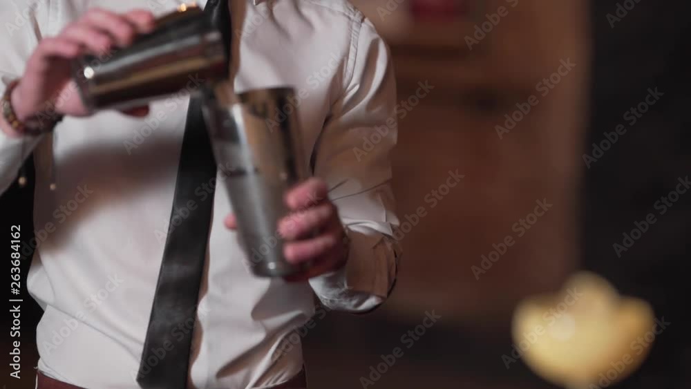Close-up of barmen's hands preparing alcoholic drink and shaking it in a bottle. Blurred view. Close-up of barmen's hands preparing alcoholic drink and shaking it in a bottle. Blurred view.