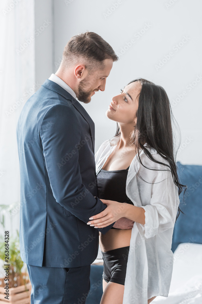 happy bearded man in suit hugging attractive girlfriend in white shirt happy bearded man in suit hugging attractive girlfriend in white shirt