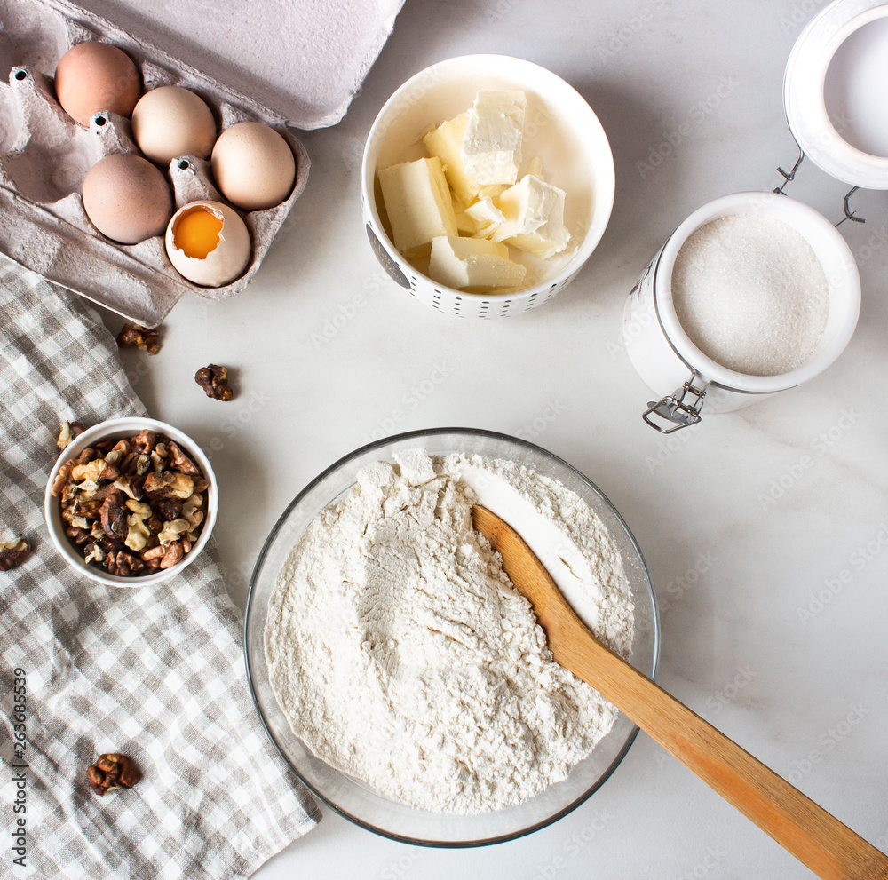 Ingredients for baking cake. Eggs, flour, sugar and whisk, butter nuts. Top view. Flatlay. Ingredients for baking cake. Eggs, flour, sugar and whisk, butter nuts. Top view. Flatlay.