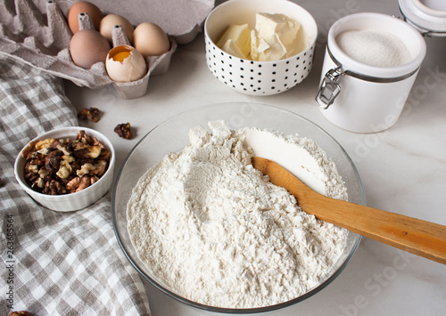 Ingredients for baking cake. Eggs, flour, sugar and whisk, butter nuts.
