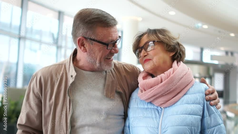 A loving mature couple at the airport waiting for their flight. Laugh and talk, a woman lays a man's head on his shoulder A loving mature couple at the airport waiting for their flight. Laugh and talk, a woman lays a man's head on his shoulder