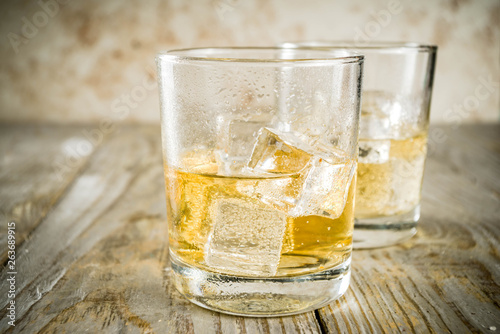 Amber Whiskey on the Rocks, alcohol drink in short glass, wooden background copy space