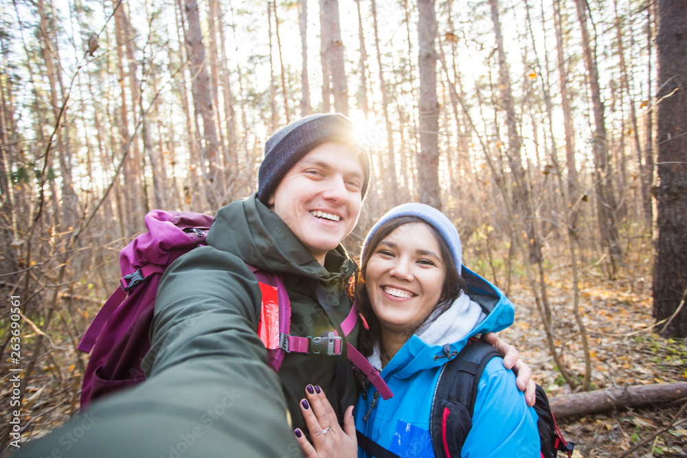 adventure, travel, tourism, hike and people concept - tourists smiling couple taking selfie over trees background