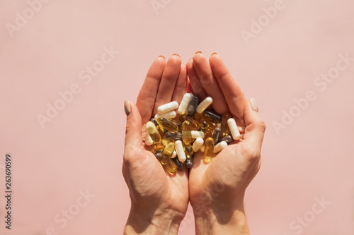 Woman's hands holding a lot of different pills or dietic supplements photo