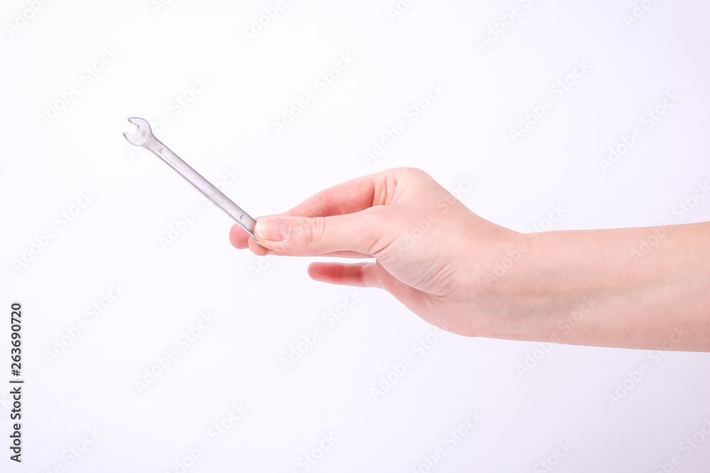A wrench in the hand of a girl. Symbol of hard work, feminism and labor day. Isolate on white background. A wrench in the hand of a girl. Symbol of hard work, feminism and labor day. Isolate on white background.
