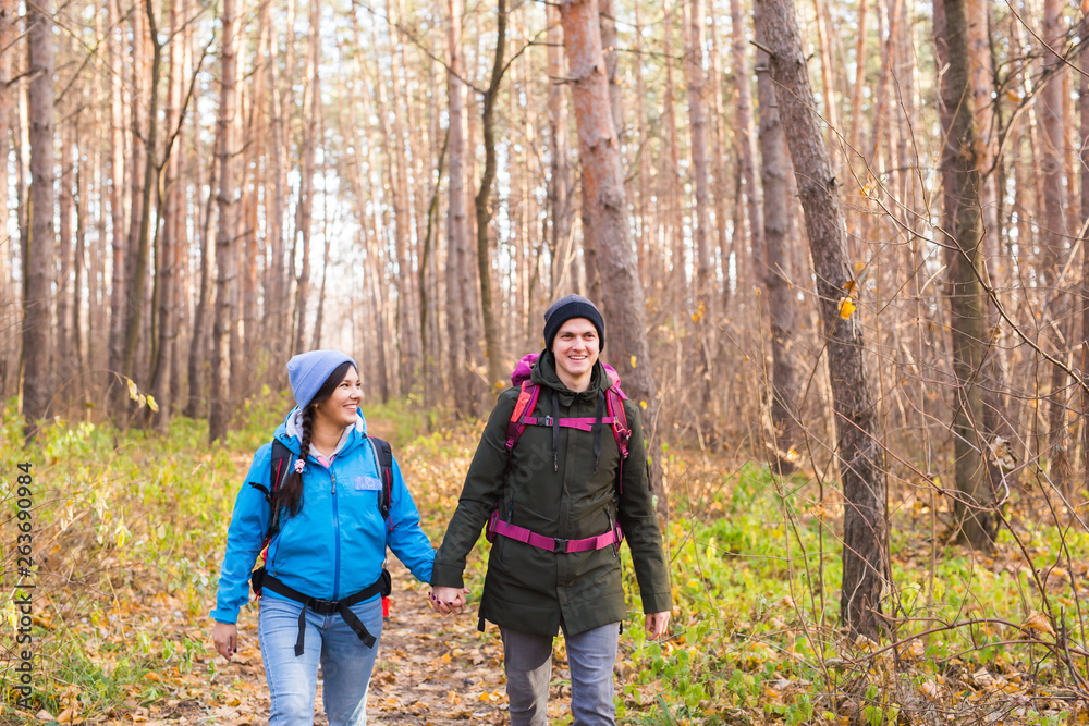 Travel, tourism, hike and people concept - Couple with backpacks walking in the autumn forest