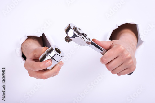 Ratchet wrench in a hand of the girl. Symbol of hard work, feminism and labor day. Isolate on white background.