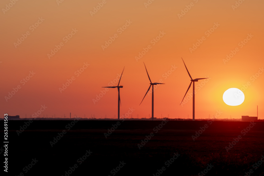 Fossil fuel and wind power in dramatic red sun set sky shot at Amager Fælled, Copenhagen, Denmark 