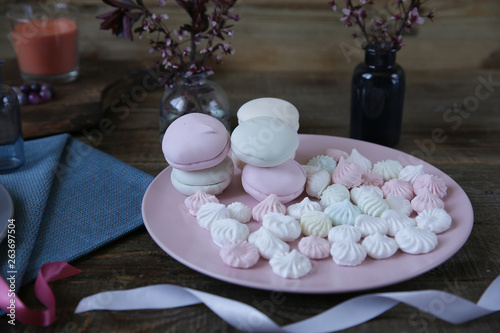 pastel marshmallow flowers on a pink plate on a rustic wooden background with spring flowers