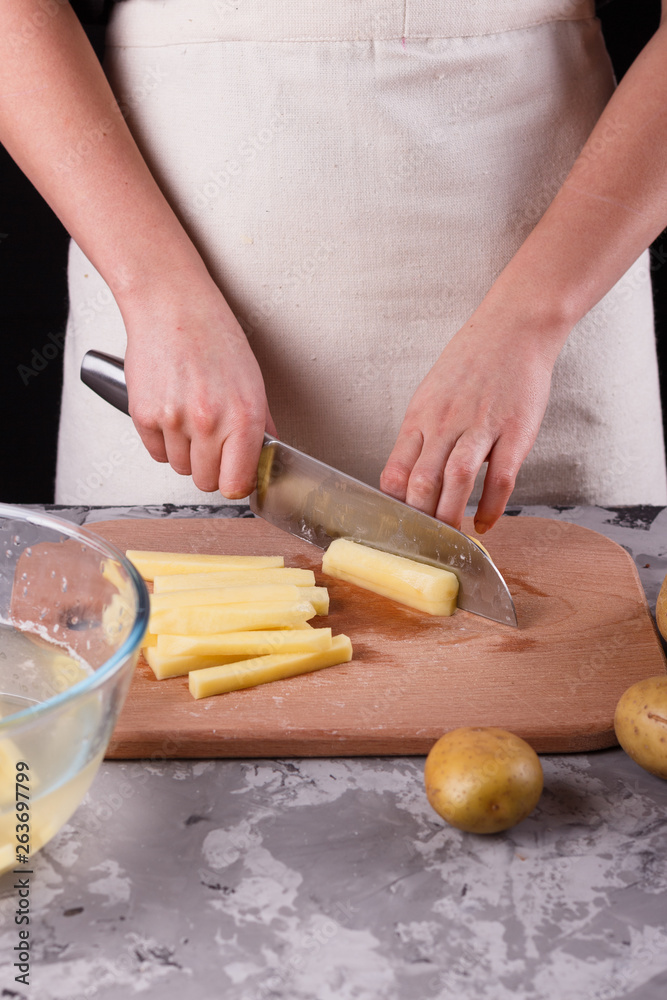 young woman in an apron cuts potatoes young woman in an apron cuts potatoes