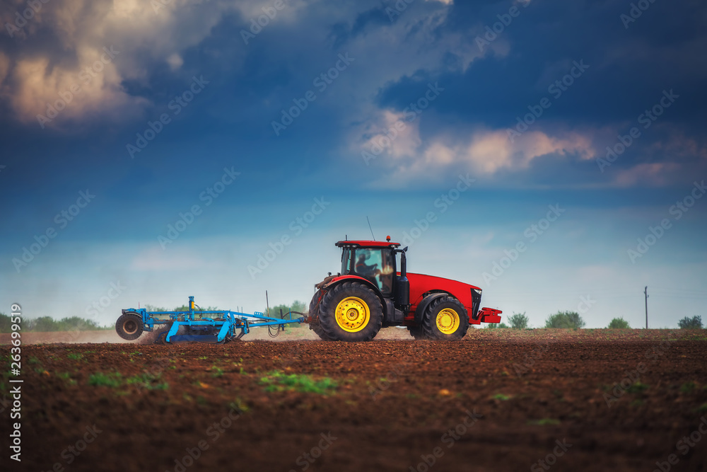 Fototapeta premium Farmer in tractor preparing land with seedbed cultivator