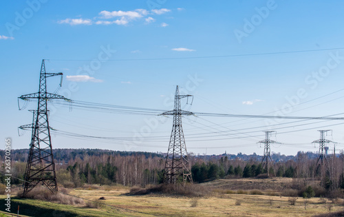 Supports high-voltage power lines against the blue sky with clouds. Electrical industry. photo