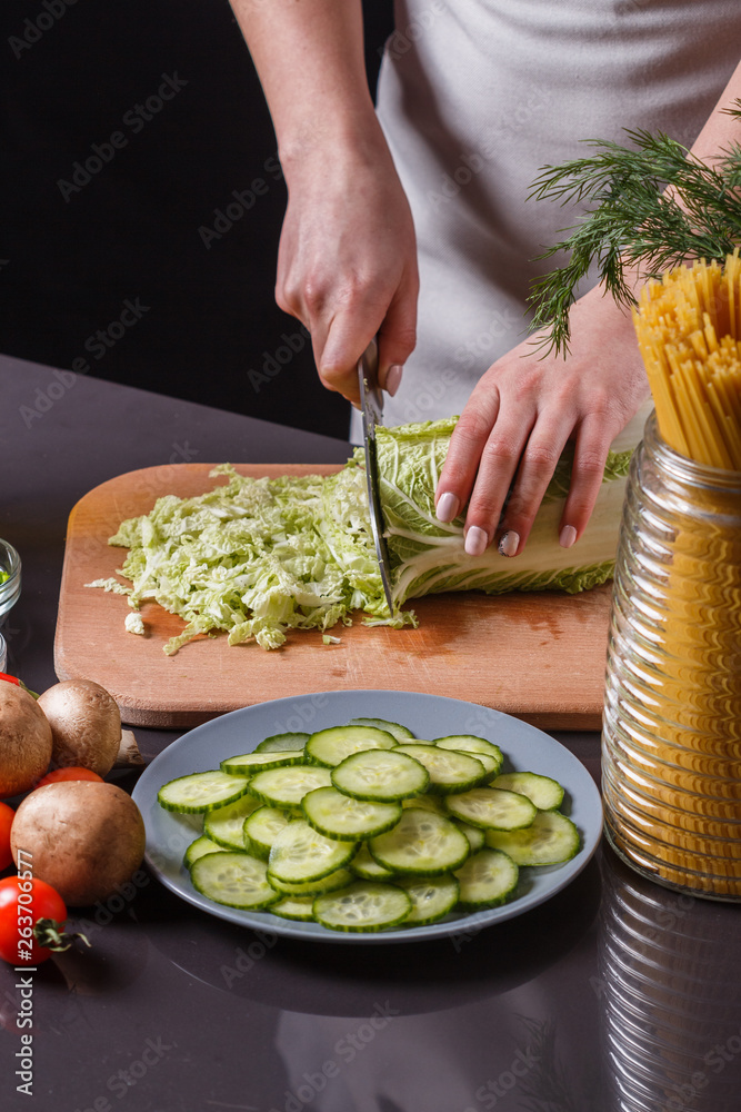A young woman in a gray apron cuts chinese cabbage A young woman in a gray apron cuts chinese cabbage