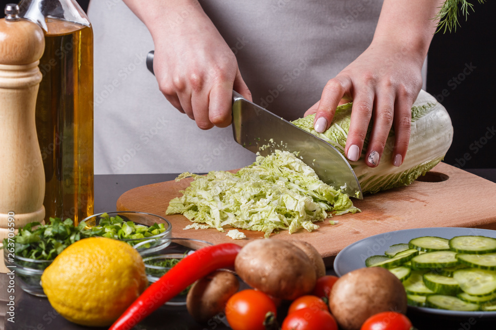 A young woman in a gray apron cuts chinese cabbage A young woman in a gray apron cuts chinese cabbage