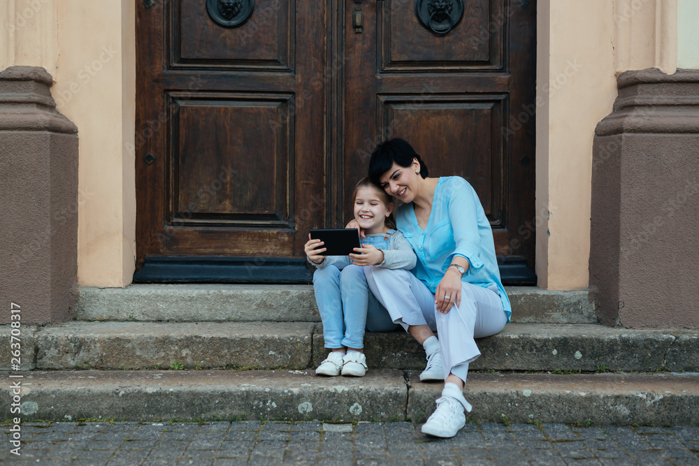 mother and daughter outdoor in town using tablet mother and daughter outdoor in town using tablet