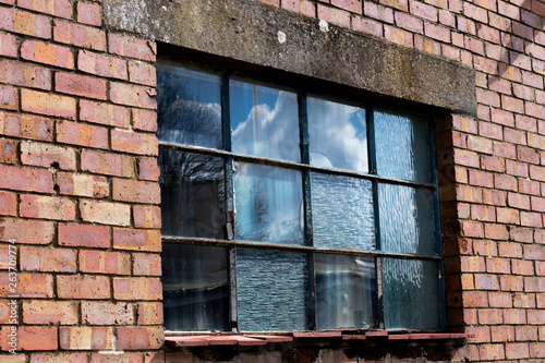 Dilapidated metal casement window frame on condemned derelict factory building awaiting demolition 