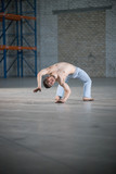 An athletic man on capoeira training. Standing on the bending over backwards position