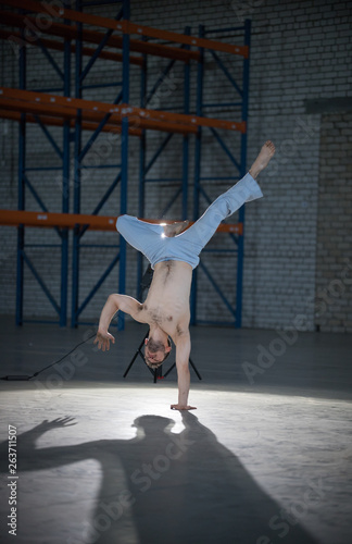 An athletic man on capoeira training. Staning in the pose. Standing on one hand