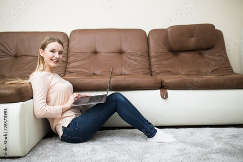 Serious young woman is studying, lying on the cozy carpet in living room at home, so nice modern interior, so comfortable atmosphere for study and work