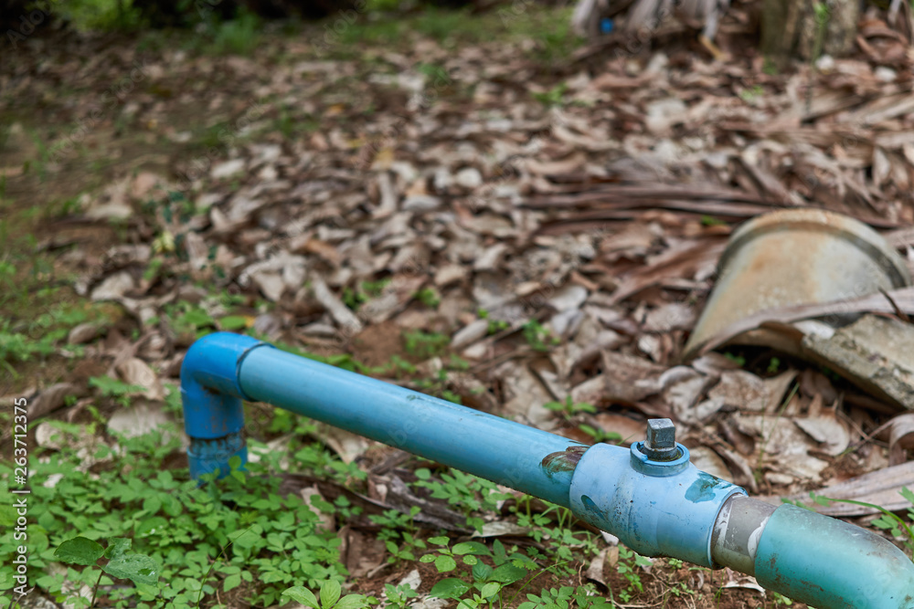 Old water valve with blue plastic pipe in garden Old water valve with blue plastic pipe in garden
