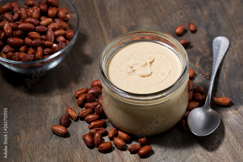 peanut butter in a glass jar on a wooden background, top view