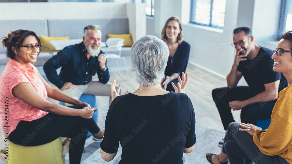 Business team sitting in circle and discussing - obrazy, fototapety, plakaty 