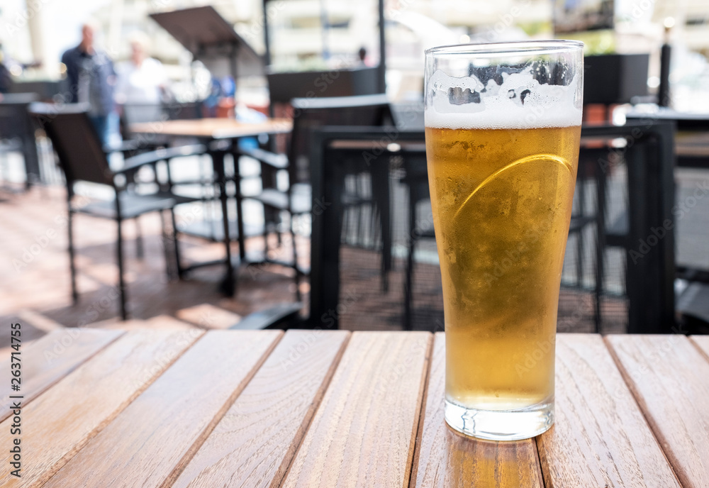 glass of cold beer with foam on a wooden table glass of cold beer with foam on a wooden table
