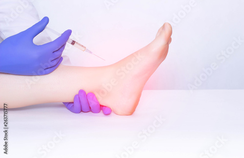 The doctor makes an injection into the ankle joint of the patient in plasma therapy to eliminate inflammation and pain, relieve edema, copy space photo