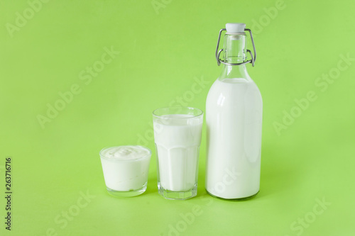 Milk kefir and sour cream are in a row on a green background. Fresh dairy products for breakfast