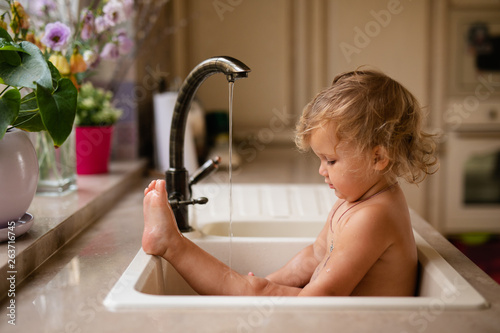 Photographie Baby taking bath in kitchen sink