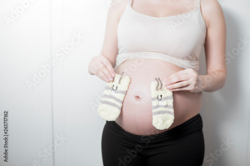 Beautiful asian pregnant woman expecting her baby with small socks