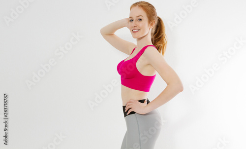 Young red haired girl in sport wear clothes isolated on white background. Slim body figure and healthy lifestyle. Fitness and sports concept. Banner © ladyalex