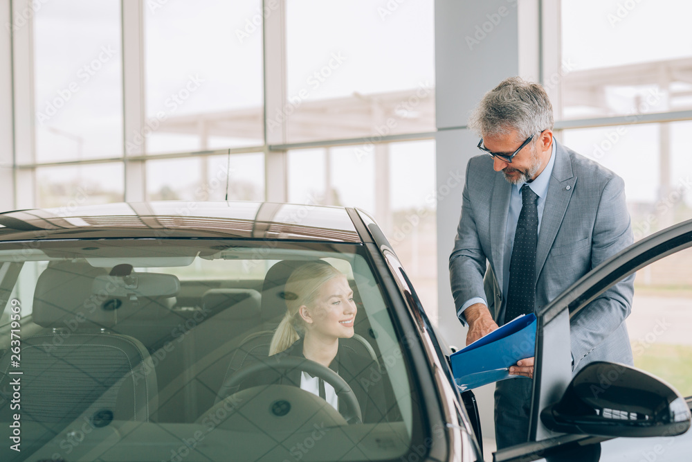 salesman showing woman brochure n car dealership showroom salesman showing woman brochure n car dealership showroom