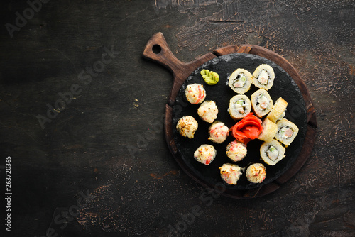 Variation of sushi and rolls on a plate. Top view. Free space for your text. On a dark background.