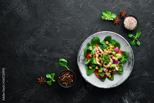 Salad with mushrooms, spinach, Turkish peas and onion in a plate on a wooden background Top view. Free space for your text. Flat lay