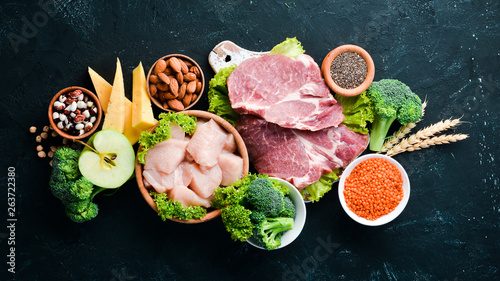 Assortment of healthy protein source and body building foods. Meat, chicken fillet, broccoli, beans, cheese, eggs, wheat. On a stone background.