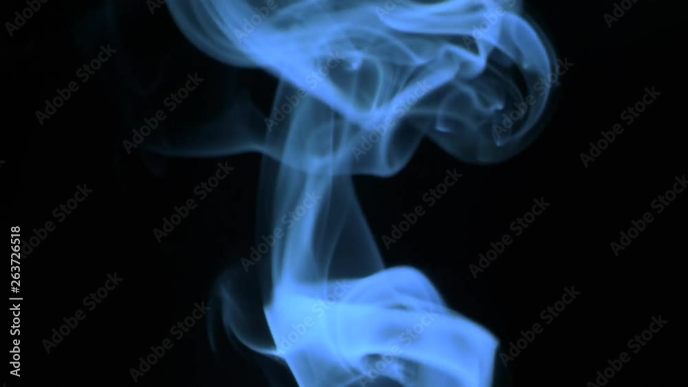 Thin trickle of blue smoke slowly rising graceful twists up on black background. Cigar smoke blowing to top. Closeup, isolated on black background.